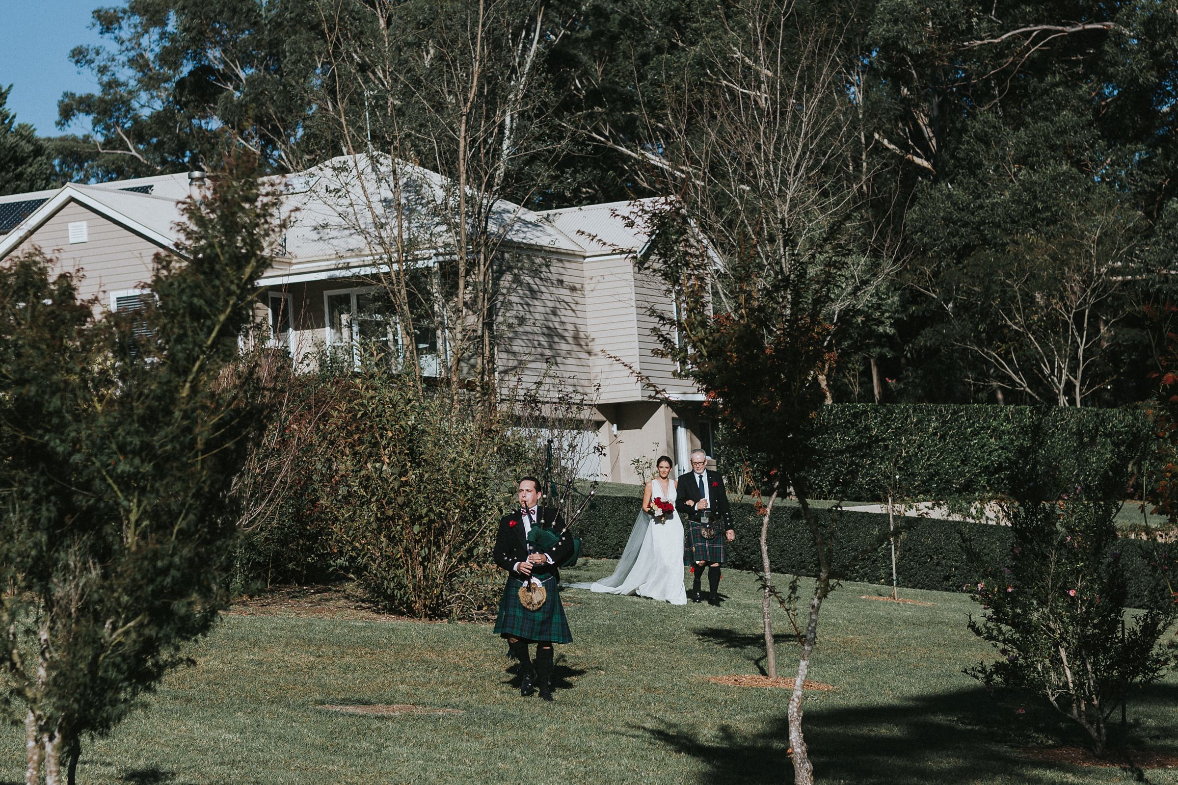 bride being walked down the aisle to the sound of bagpipes being played by her brother