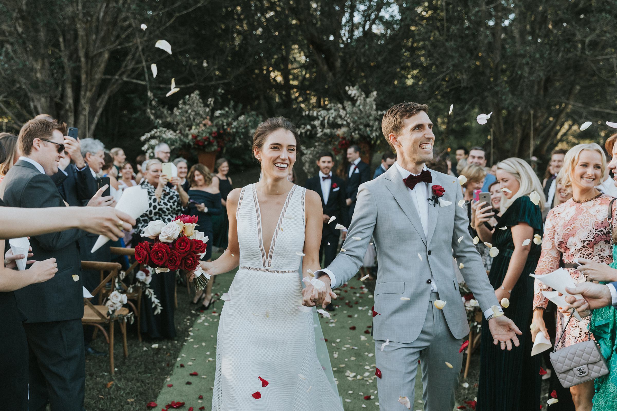 rose petals and confetti being thrown at bride and groom at wedding ceremony