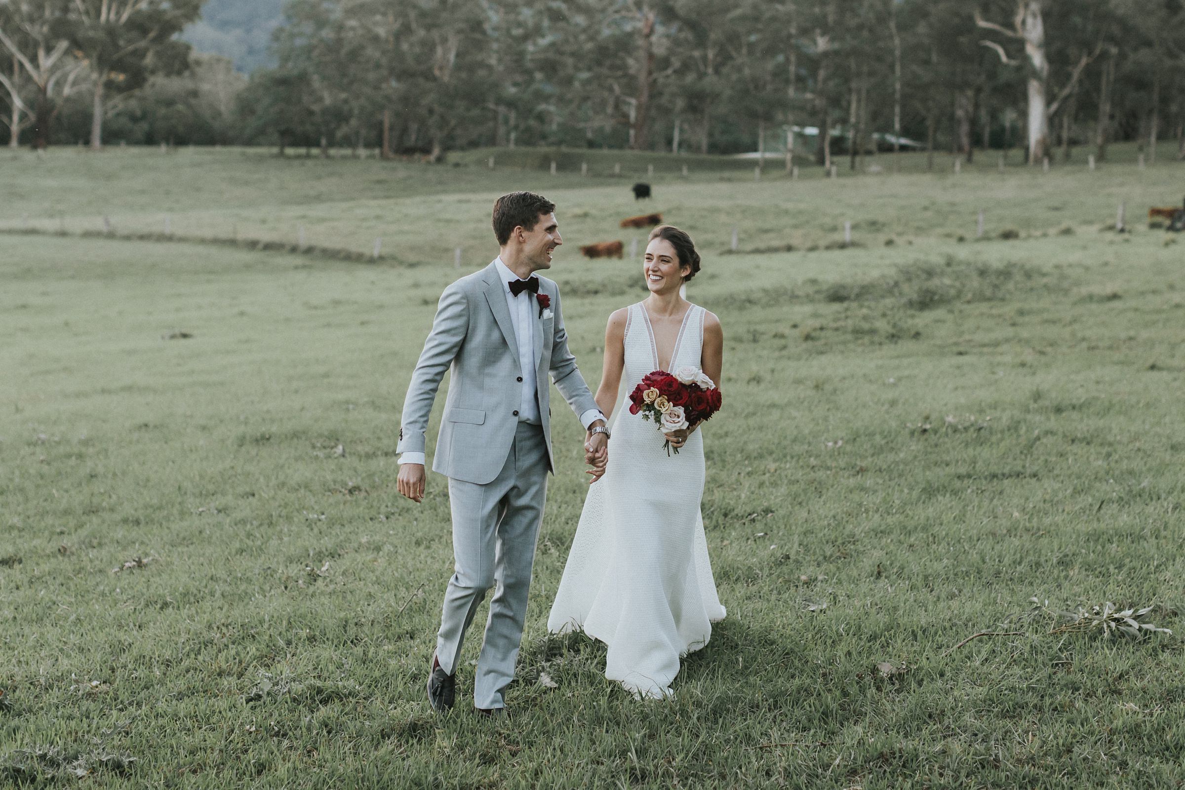 bride and groom walk through paddocks for wedding portraits