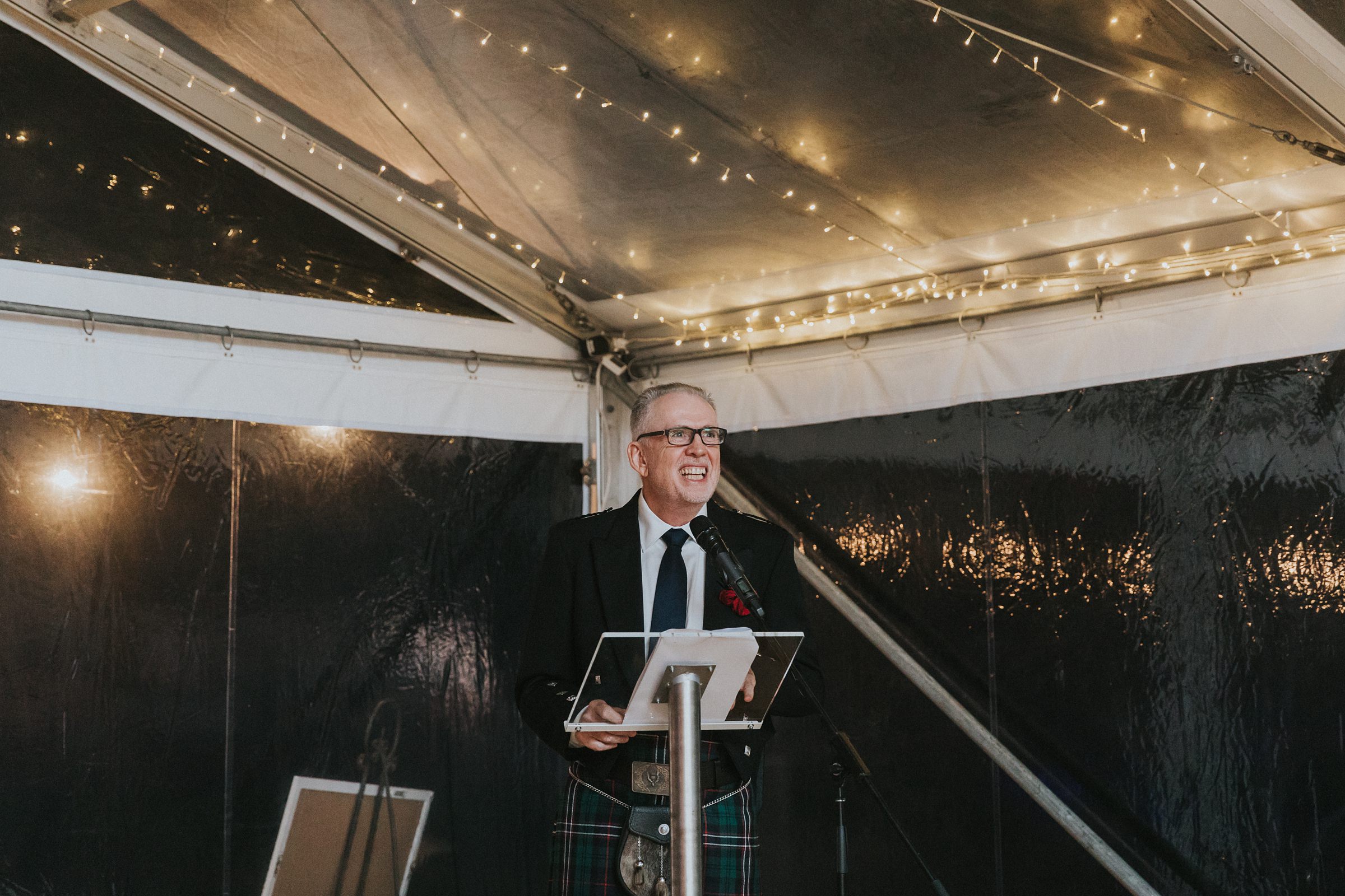 father of the bride beaming with pride during speech in marquee